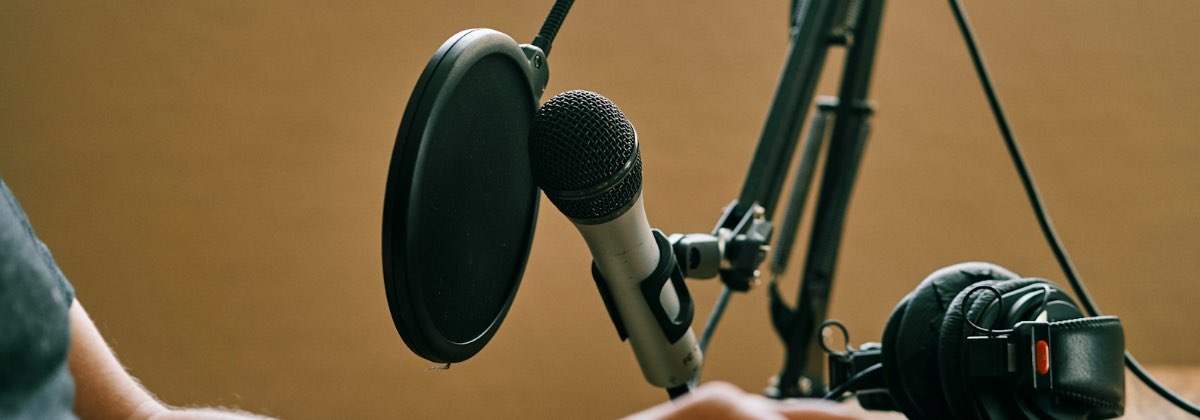 Podcaster speaking into a condenser microphone using downward expansion to remove hiss