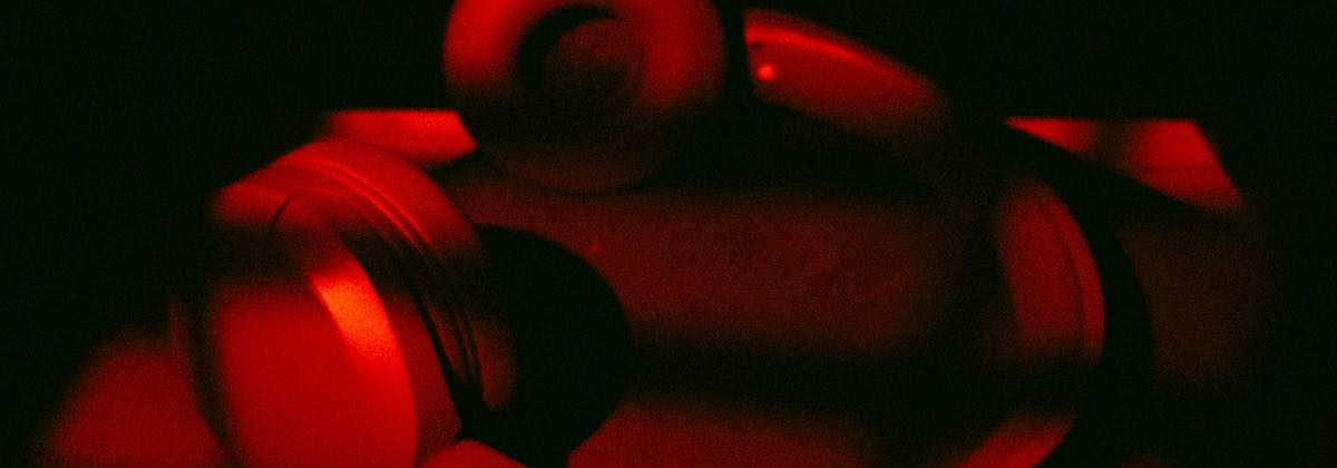 Rote Kopfhörer auf einer dunklen Oberfläche, mit denen die Reverb-Einstellungen eines Slowed-Edits geprüft werden