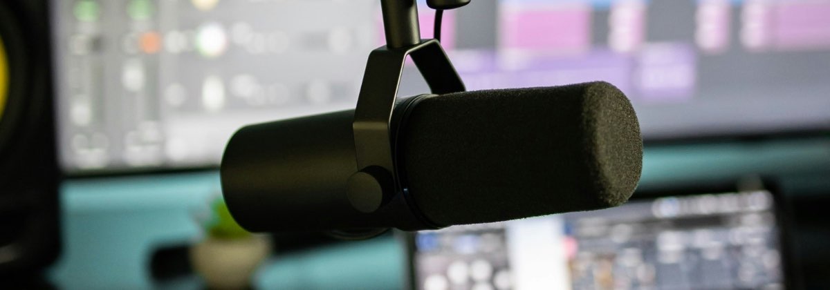 A studio microphone in front of a computer monitor displaying vocal pitch analysis software